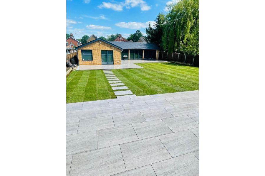 Travertine Dark porcelain patio with large lawn leading to another patio area with stepping stones.