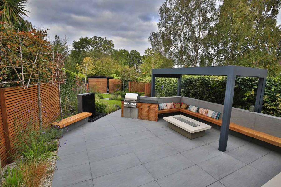 Patio in Trendy Black Porcelain. Pergola over fire-table and benches cantilevered into wall faced in matching porcelain tiles.
