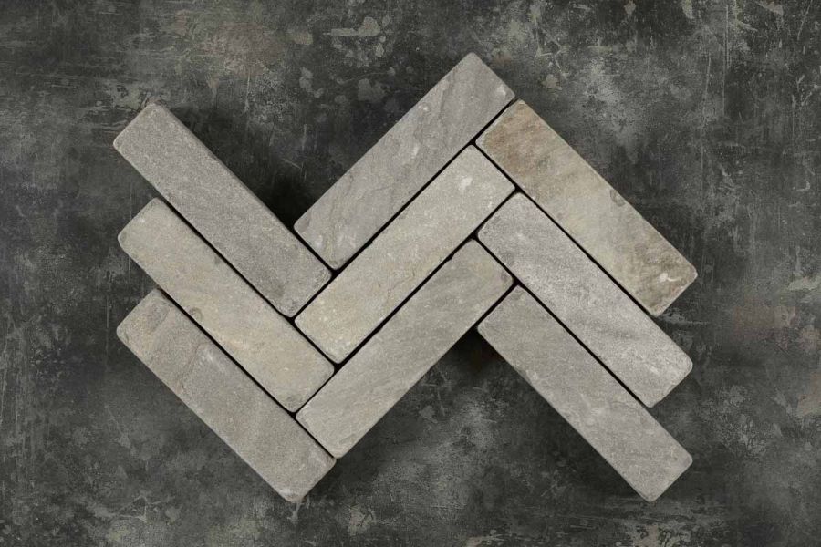 9 tumbled Black sandstone patio bricks placed in 3 rows, zigzag pattern, against dark background. Free UK delivery available.