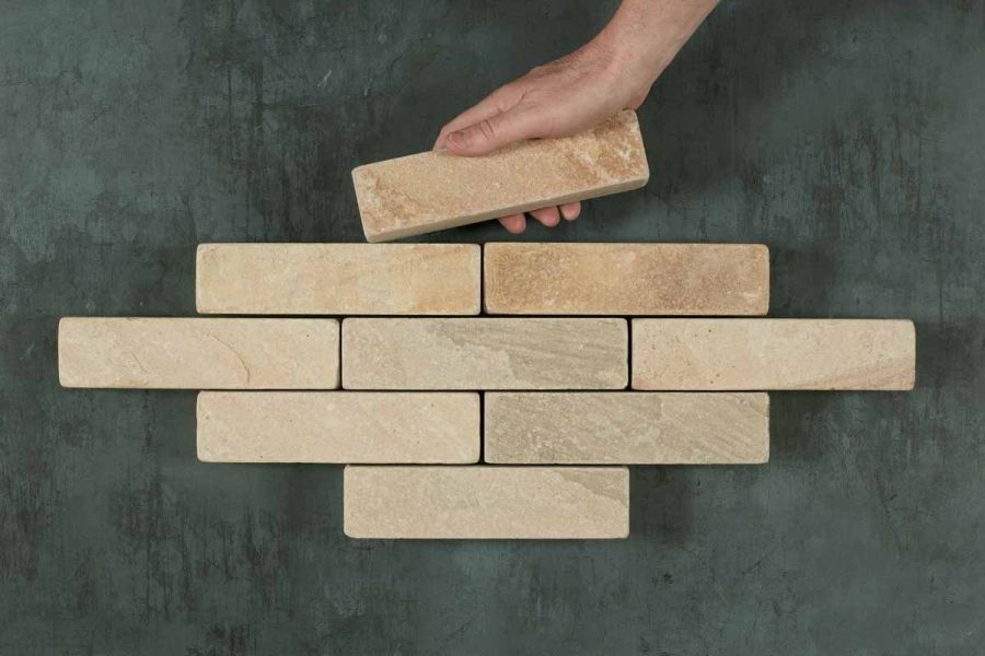 Hand adds 9th stone paver to 8 Mint sandstone patio bricks arranged in 4 rows in lozenge shape. Free UK delivery available.