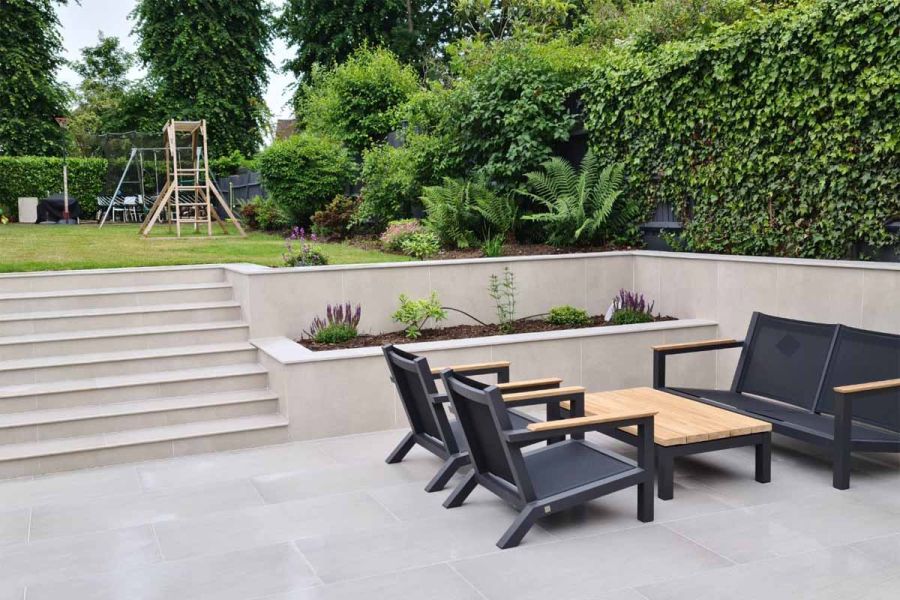Patio area paved with Urban Grey vitrified porcelain paving, featuring modern metal garden furniture set with a wooden top.