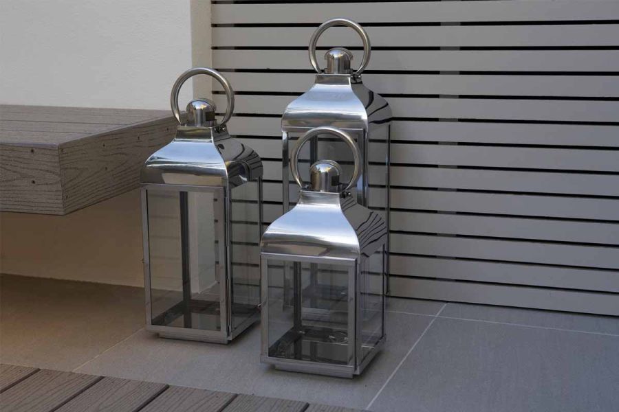 Three silver lanterns stand on Urban Grey Vitrified Porcelain tiles next to composite decking and matching cantilevered bench.