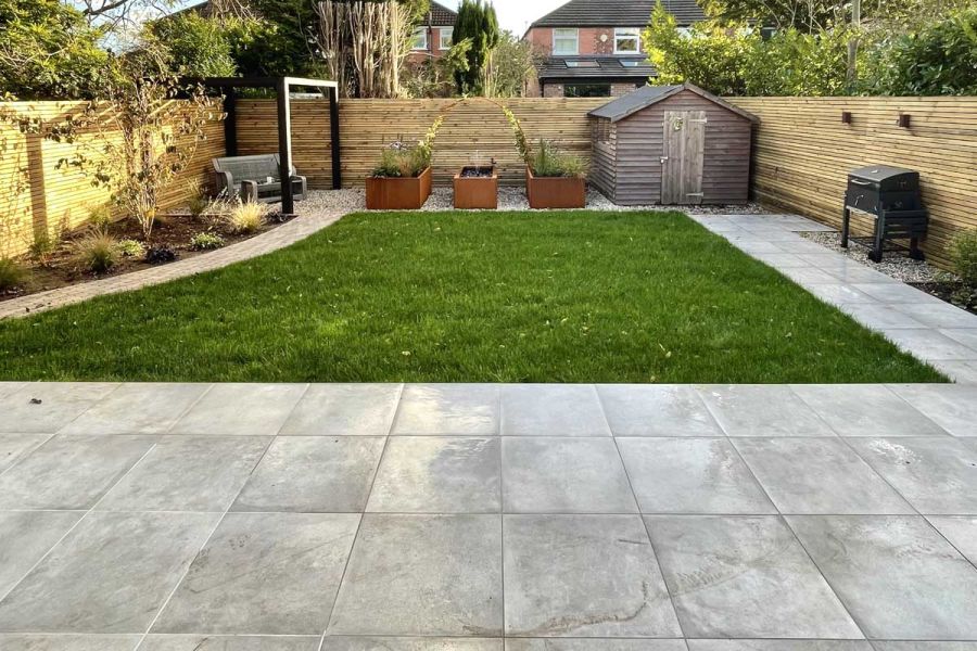Rear family garden screened on all three sides with a central lawn and paved with Venetian Grey Porcelain paving.