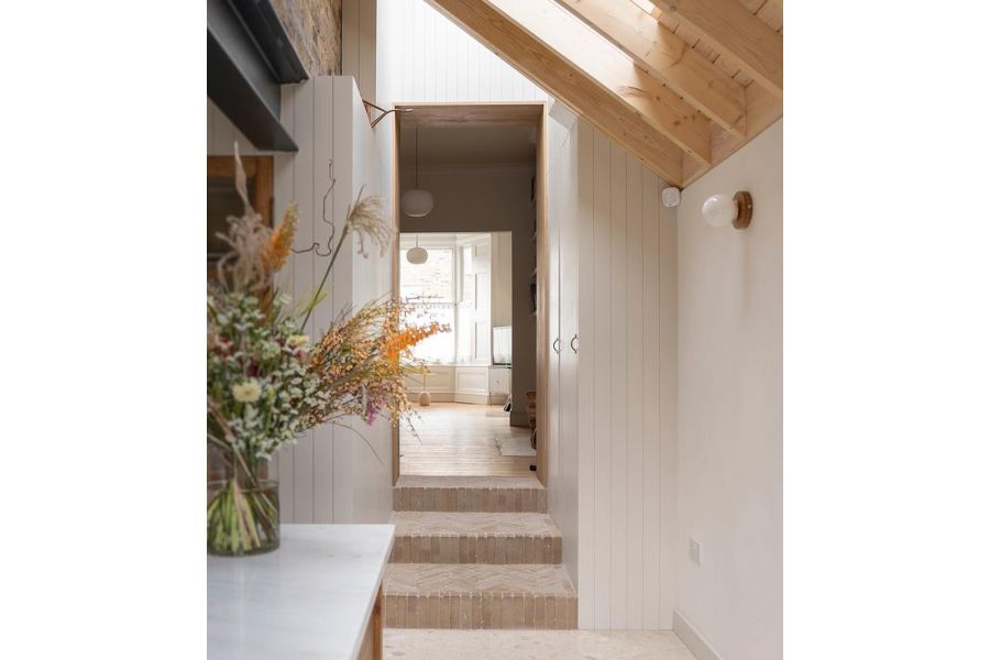 White-painted narrow interior with 3 steps of Westminster Clay Pavers up to large, light-filled, wood-floored room. 