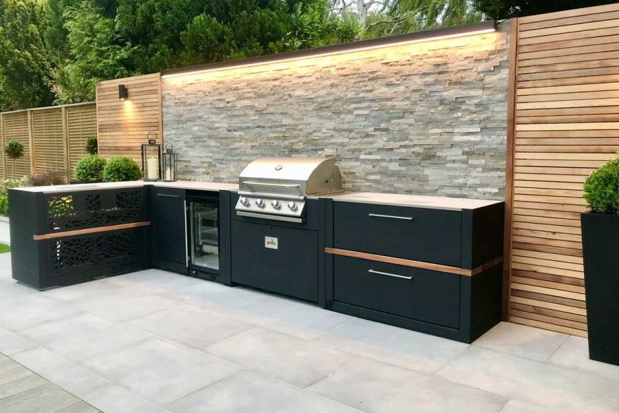 Outside cooking area including an impressive BBQ and grill, with Grey Wall Cladding and downlights, with Venetian Grey Porcelain Paving.