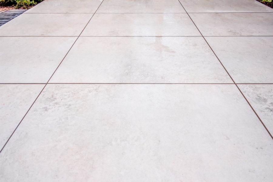 Large rectangular Light Grey Porcelain paving slabs laid in a grid pattern and jointed with dark grey exterior grout.