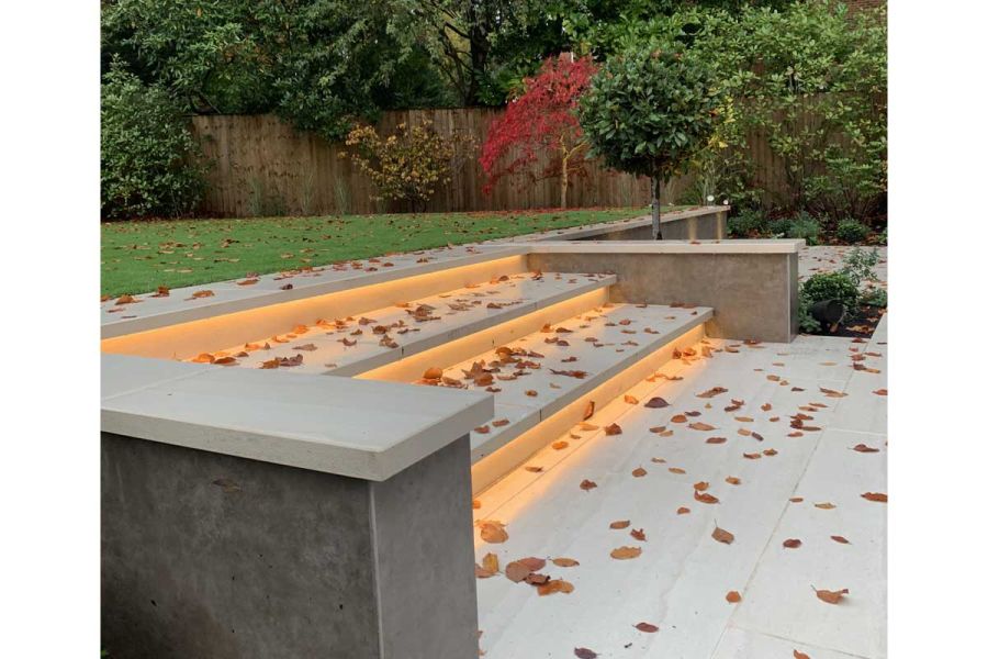 Walls faced with Vulcano Ceniza Luxury flank 3 wide cream porcelain steps scattered with fallen leaves. Design by Waratah Gardens.