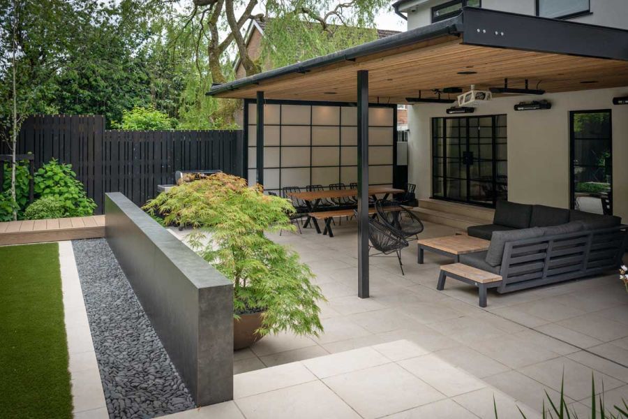 Japanese style garden with covered paved patio divided from lawn by wall faced with Vulcano Roca grey external cladding.
