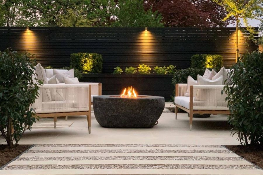 Golden Stone Porcelain plank paving, set in gravel, fronting patio with stone firepit and white furniture designed by Waratah Gardens.