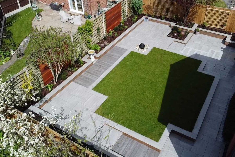 Birds eye view looking down onto  a large lawn paved on all sides with Kandla Grey and Wood Effect Porcelain.