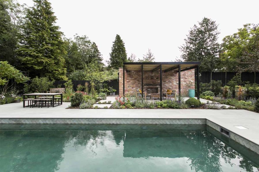 Planted beds set into Yard Large Porcelain slabs which pave swimming pool surround and adjoining pergola-covered seating area.