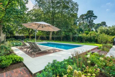 Sun loungers and cantilevered parasol sit on Antique Red pavers set into Dove Grey sawn sandstone paving surrounding swimming pool.***Graduate Landscapes,  www.graduatelandscapes.co.uk