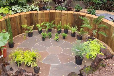 Autumn Brown Sandstone Circle edged by planting, with sinuous path leading to large wooden garden room. By No.30 Design Studio.***No.30 Design Studio, www.no30design.co.uk