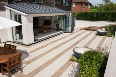 Modern house extension with bi-folding doors opening out onto a large porcelain patio of Faro and Rovere porcelain paving.***Design by Caroline Davy Studio, www.carolinedavy.co.uk | Built by PC Landscapes, www.pclandscapes.co.uk