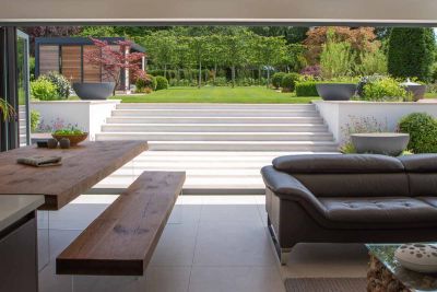 View from inside boasts glorious views of Faro Porcelain Steps leading up to large lawn area. Design by Caroline Davy.***Designed by Caroline Davy Studio, www.instagram.com/carolinedavystudio | Built by PC Landscapes Ltd, www.pclandscapes.co.uk
