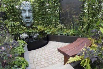 Raj Green cobble setts form deep arc between black raised bed with lush planting and curved wooden bench. Design by Richard Rogers.***Richard Rogers Designs, www.richardrogersdesigns.com