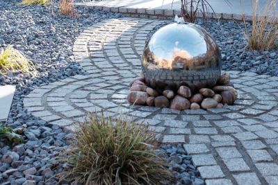 Silver ball water feature sits on cobbles in midst of silver grey granite sett circle edged with gravel. By Vu garden design.***Vu Garden Design & Landscaping, www.vugarden.co.uk