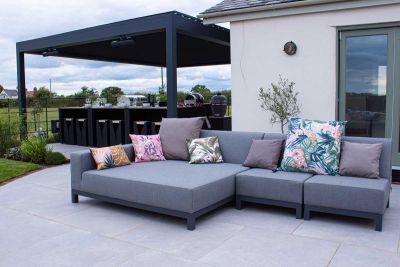 Polvere porcelain Large Paving Slabs paved under a large black pergola with BBQ and dining area and relaxing outdoor furniture.***Design by Urban Landscapes, www.urbanlandscapedesign.co.uk | Built by Walker Landscape & Design, www.walkerlandscapeanddesign