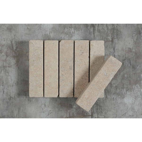 5 Egyptian Beige limestone patio bricks against a grey background, showing markings, with 6th balanced at an angle on top.***