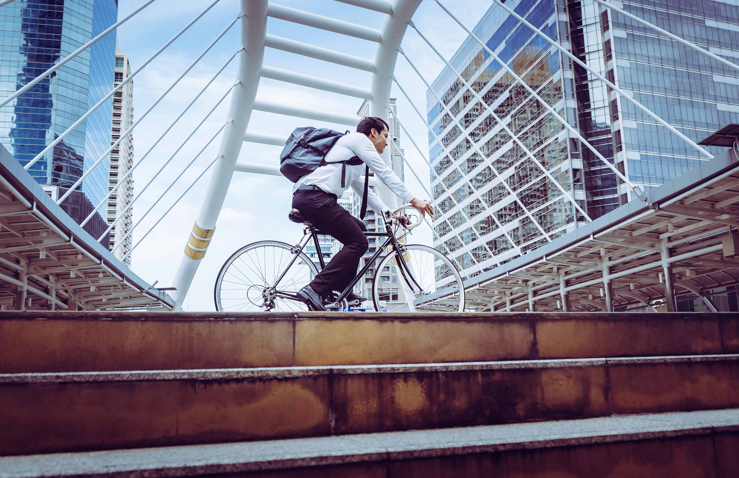 Panning shot of man on bicycle against modern architecture.