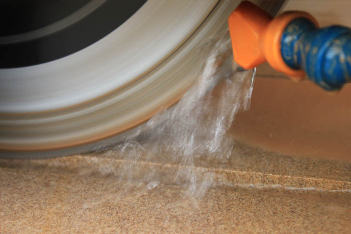 Water cools the cutting blade as it calibrates Indian sandstone paving.