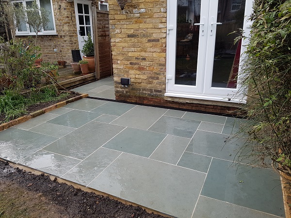 Small rectangular patio outside french doors showing the colours of Kota Blue limestone slabs when wet.