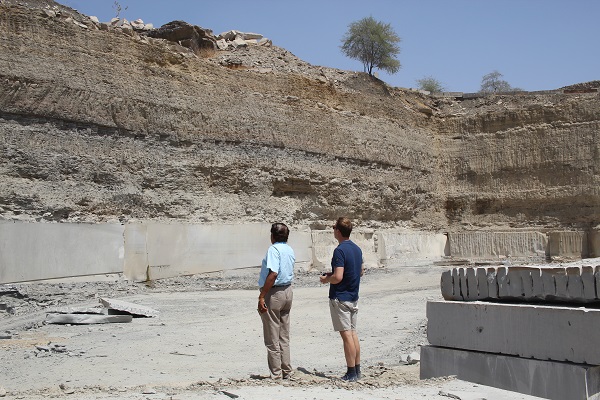 2 men standing at bottom of quarried area of sandstone. 
