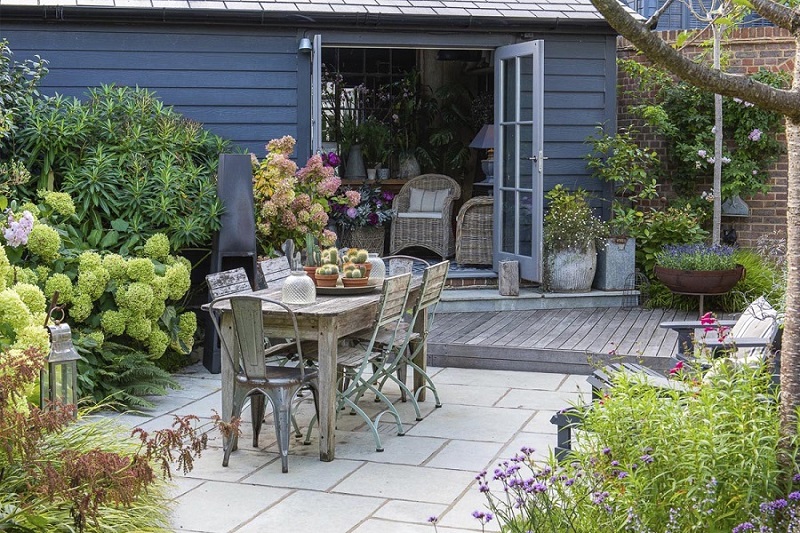 Kota Blue limestone clean patio with outdoor furniture by summer house.