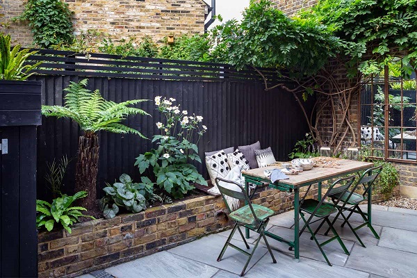 Kandla Grey Indian sandstone patio with brick raised bed along fence and garden dining set