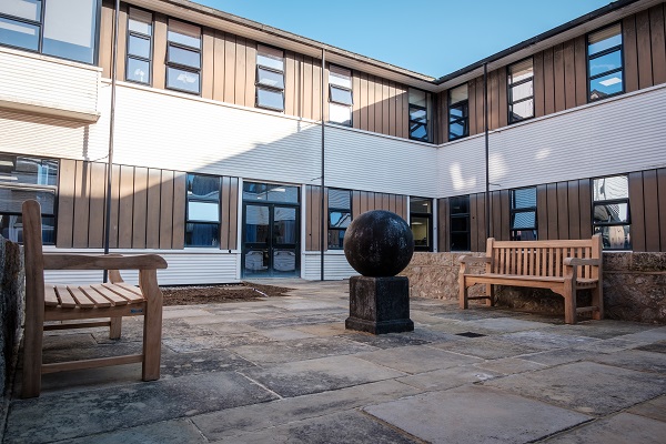 View across courtyard to internal corner of apartment building, with sculpture and benches.