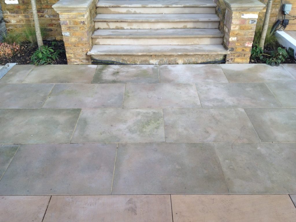 Steps down to sandstone paving turning green with algae
