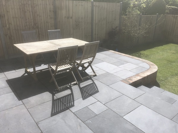 Raised patio laid with Midnight Black limestone project pack and brick edging.