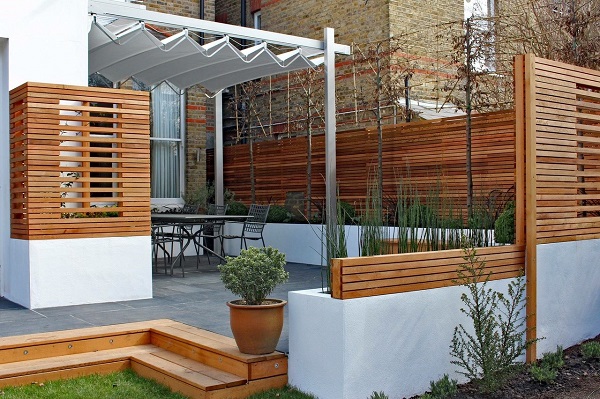 Patio in black limestone with red brick steps and white pergola