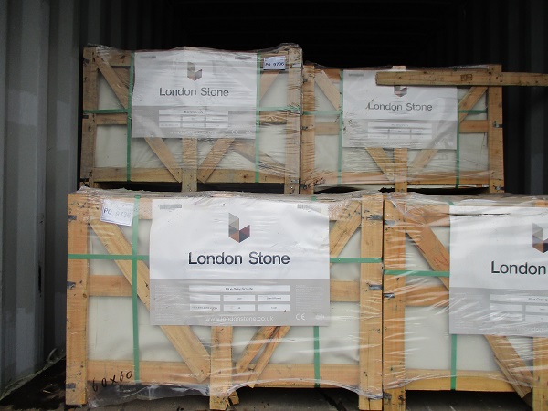 Stacked wooden crates of paving, shrink-wrapped, with labels attached