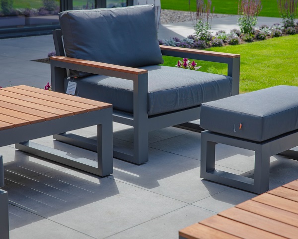Modern grey rectangular chair and footstool on Steel Grey porcelain 900x600mm patio tiles, laid stack bond.