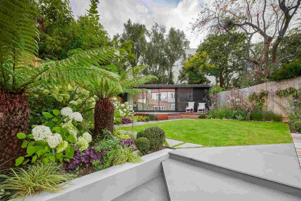 Angled steps of large format Yard porcelain paving rise to rectangular lawn.