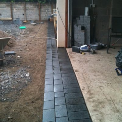 Black basalt setts laid as edging before laying silver grey granite in main body of paving.