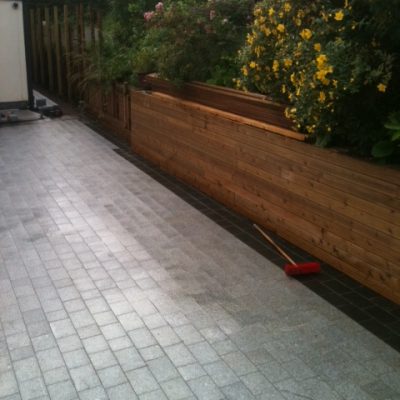 Silver grey granite with basalt edging next to wooden sleeper retaining wall.