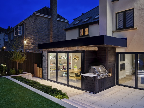 Comblanchien porcelain paving laid stack bond with dark pointing outside sliding patio doors. Night scene. 