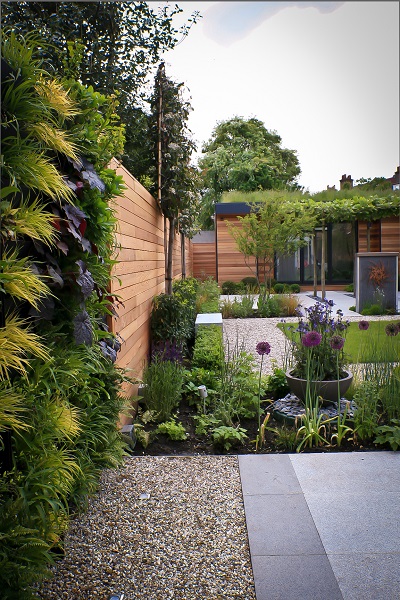 Silver grey sawn granite paving next to gravel and planted bed. 