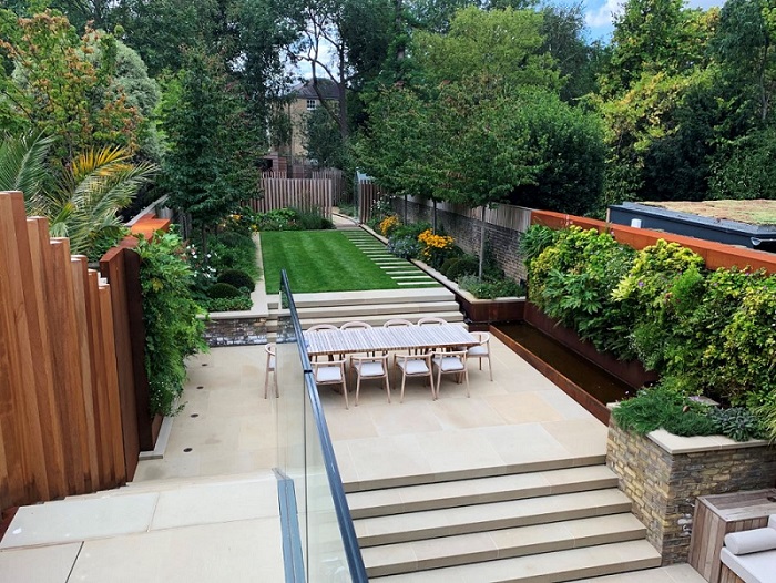 Long garden part paved with Britannia Buff Yorkstone, with wide steps up to patio