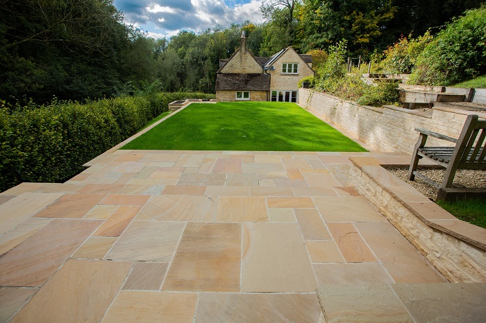 Looking down long lawn to house from large patio in Camel Dust riven sandstone 
