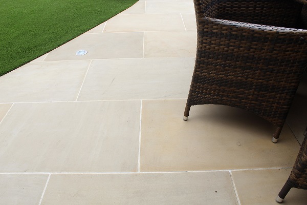 Close view of Harvest sawn sandstone with rattan furniture leg and lawn. 