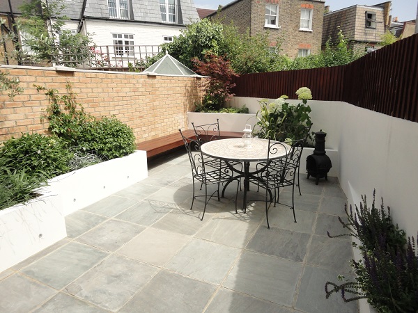 Courtyard paved with Kandla Grey low cost paving, with raised beds and outdoor dining set.
