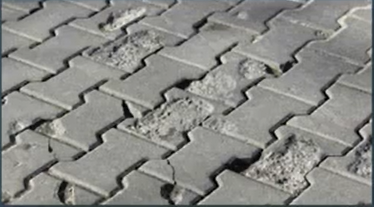 grey interlocking concrete pavers with survace damage shwoing aggregate beneath