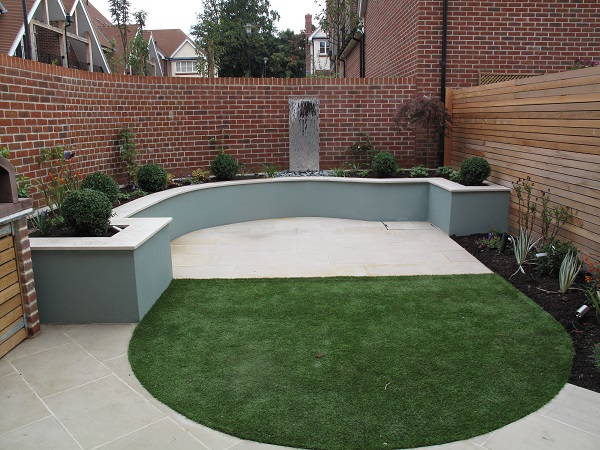 Bespoke Beige sawn sandstone coping curves around patio by matching apron of grass.