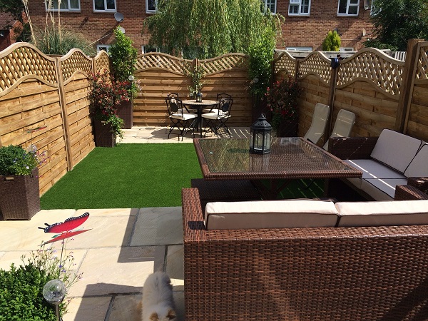2 Mint Indian sandstone patios  at either end of small narrow garden, separated by artificial grass. 