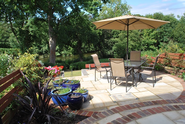 Furniture and parasol sit on circular Mint sandstone patios which intersect each other.