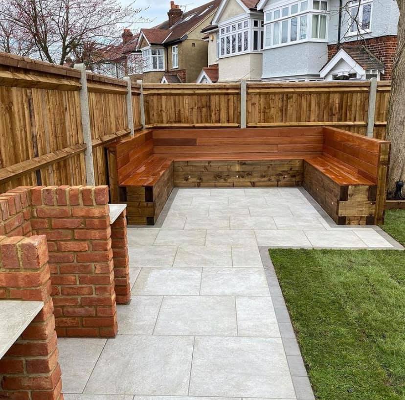 Steel grey porcelain setts edge patio area in corner of fenced garden.