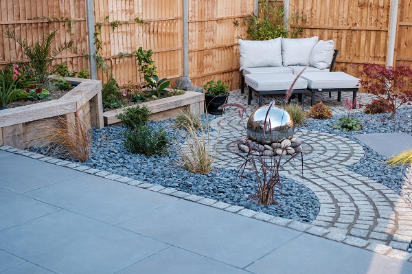 Silver grey granite setts in curved path and feature circle with silver ball sculpture on top.